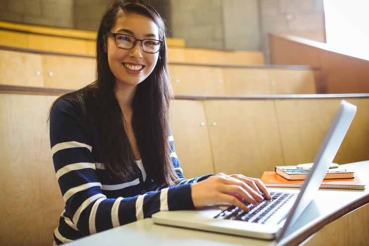 Smiling student using laptop at the university