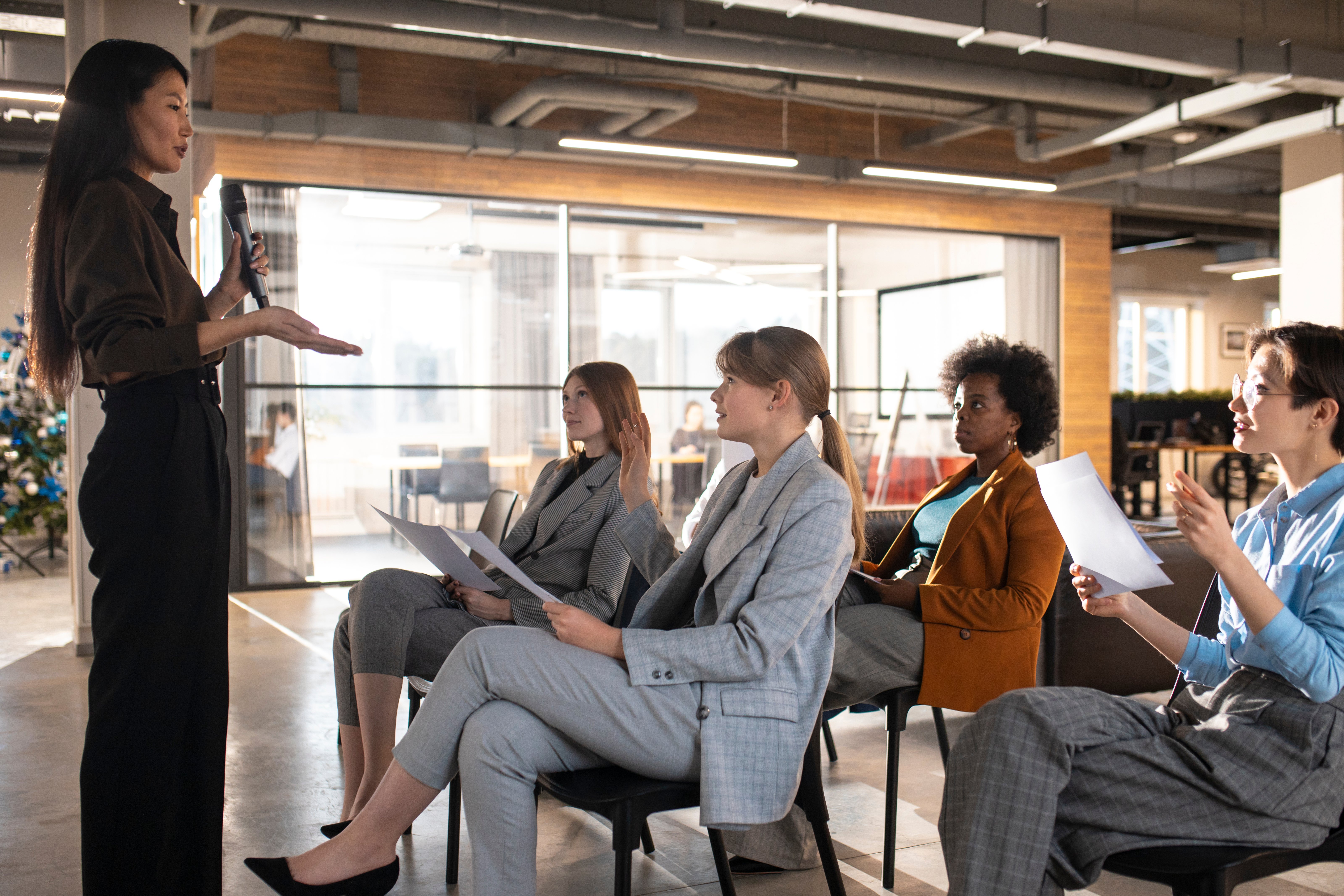 Professional woman giving a presentation to colleagues in a modern office, representing the soft skills needed in accounting careers.