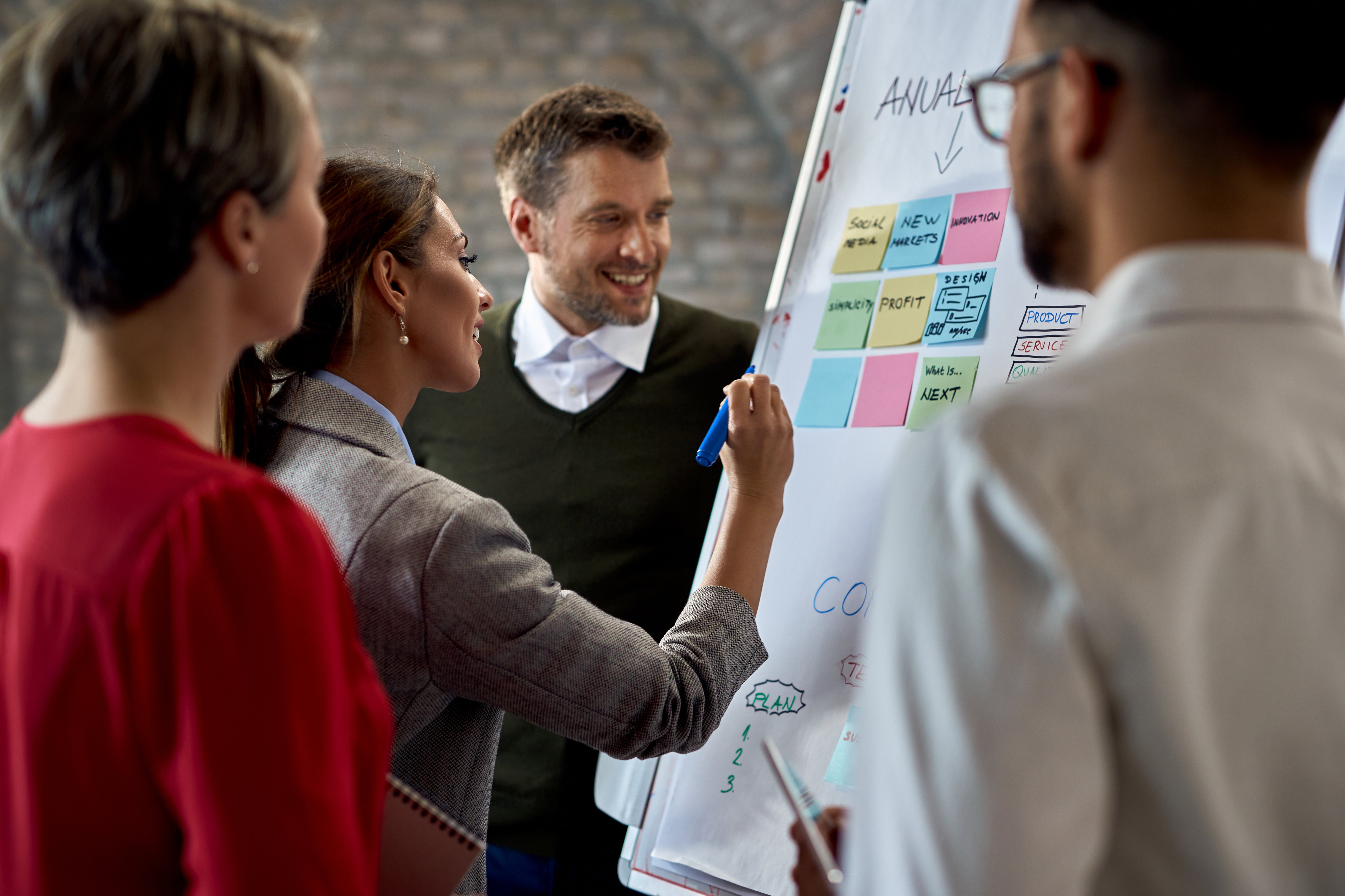 Diverse business team collaborating at a whiteboard, representing strategic thinking and future career opportunities in business and marketing.