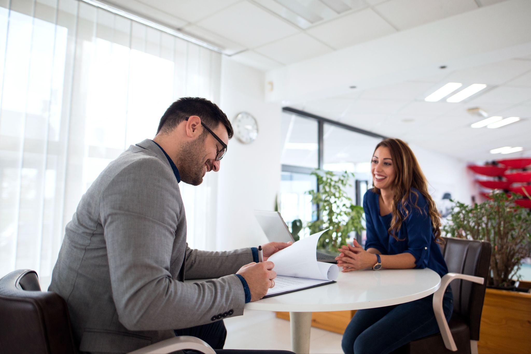 Hiring manager smiling while reviewing a candidate's document during a positive interview.