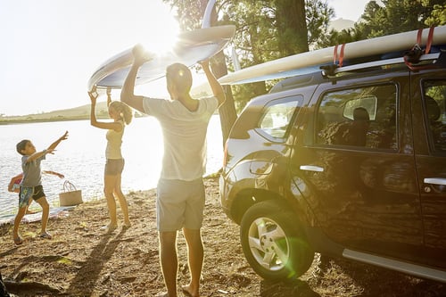 Family unloading paddle boards at beach