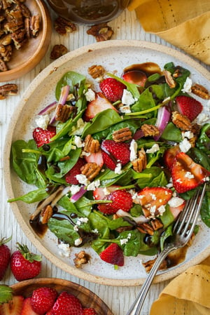 An overhead shot of a Strawberry Spinach Salad on a plate with chopped pecans