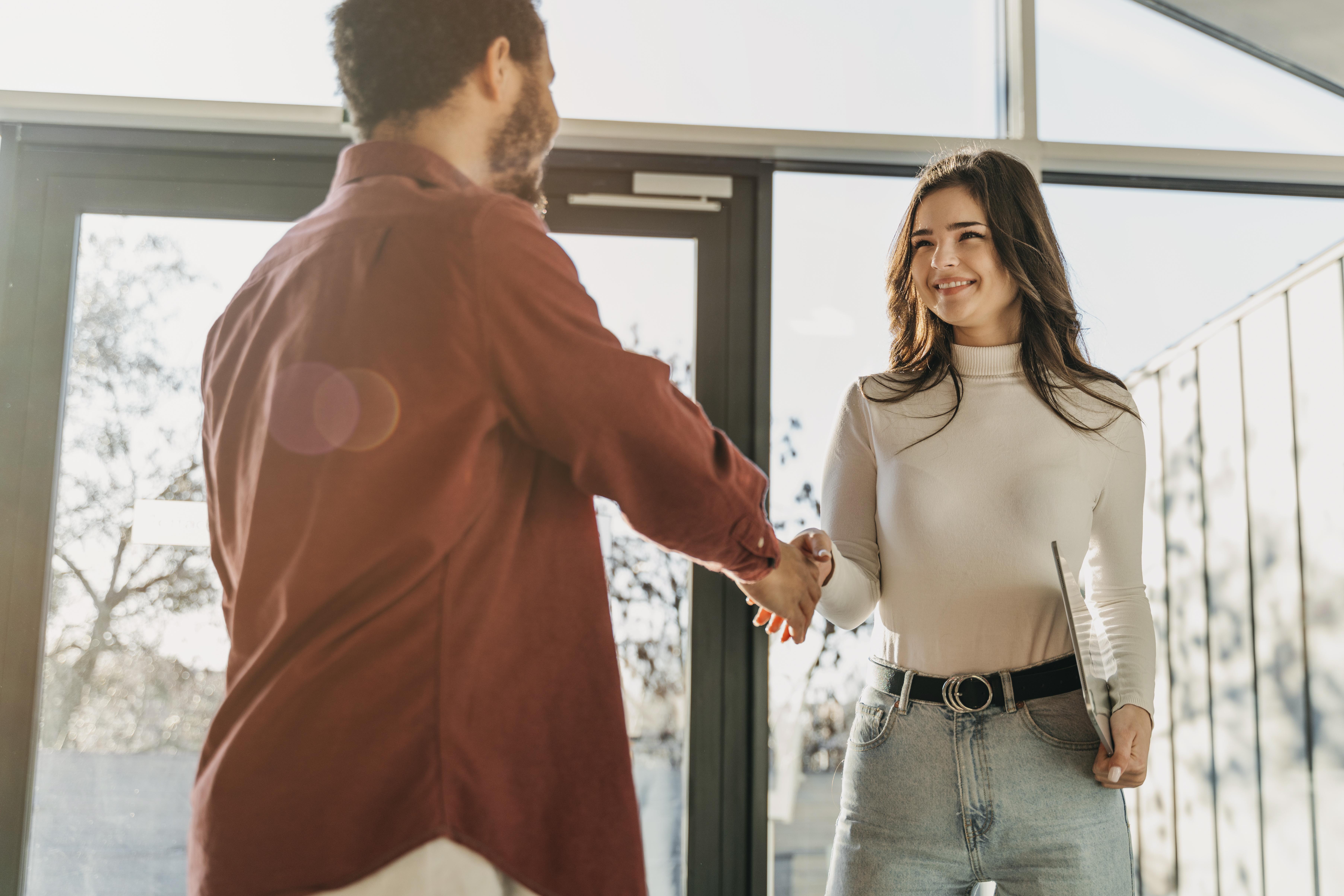 Young professionals shaking hands in a bright office, representing career readiness in the best industries to work in 2025.